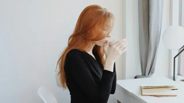 Woman enjoying a calm morning with her journal and coffee, practicing daily affirmations
