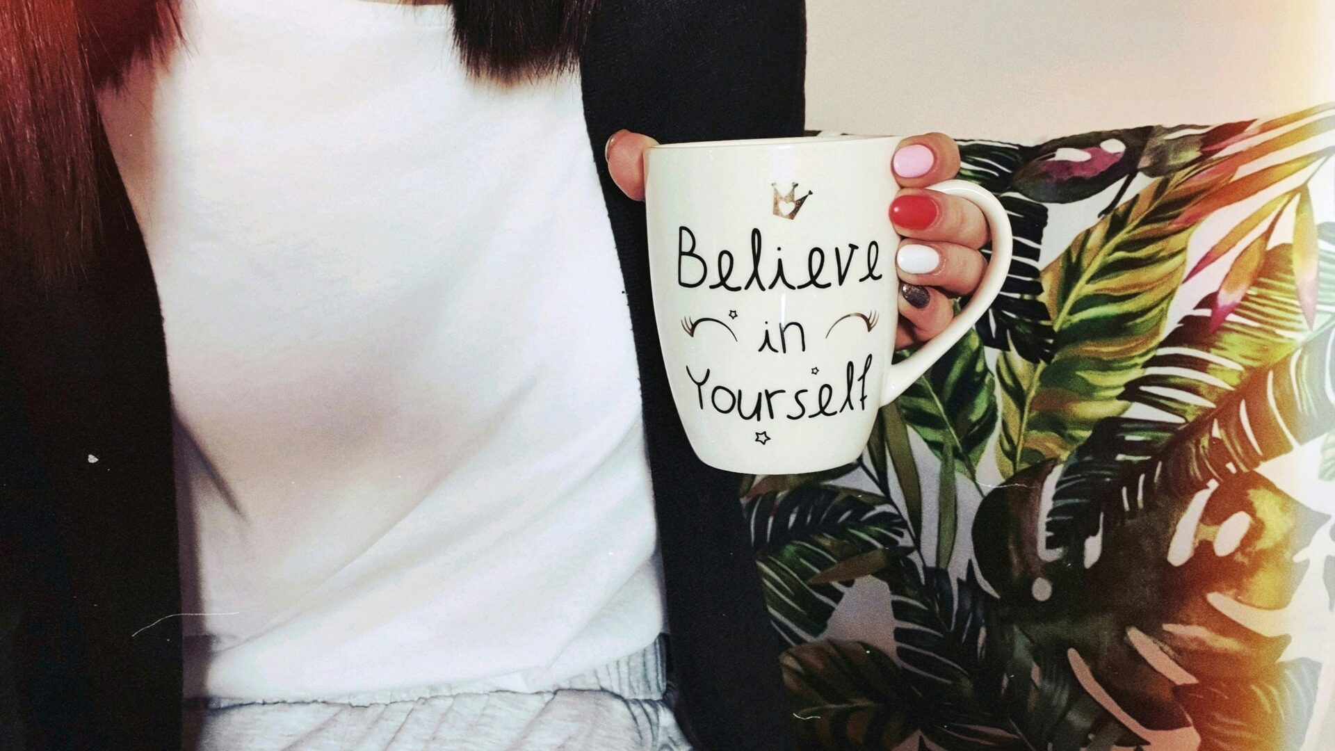Woman holding a coffee mug with the words Believe in Yourself, symbolizing confidence and self-belief