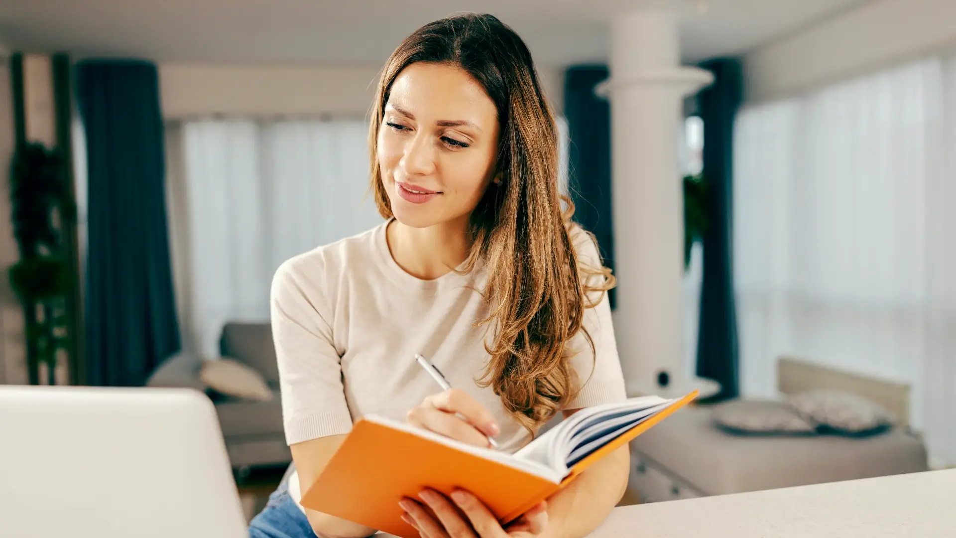 Woman writing in a journal at home, reflecting on personal growth and starting fresh.
