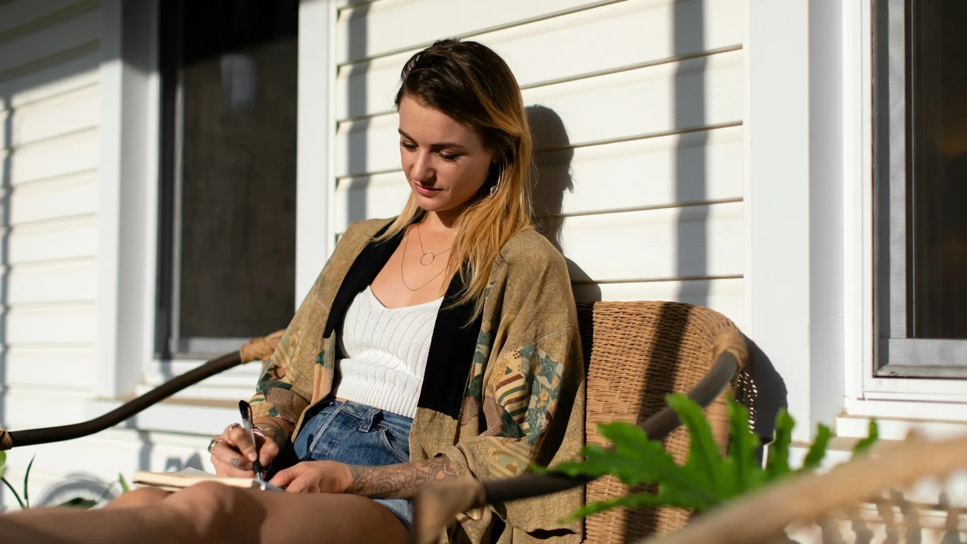 Woman writing in her journal outdoors in the sunlight, building a mindful journaling habit — iAmEvolving™ Journal inspiration