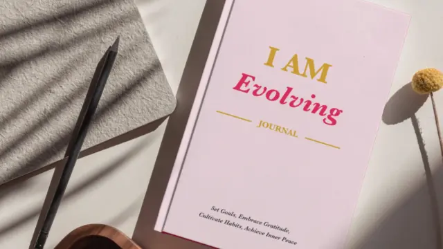 iAmEvolving Journal on a desk with daily journaling prompts written inside.