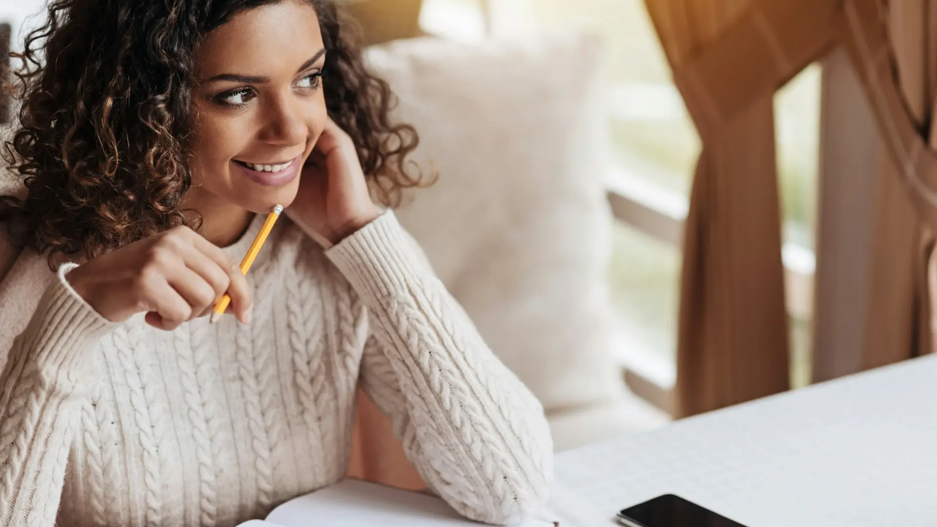 Woman smiling while writing in a guided journal with prompts for self-discovery and mindfulness.