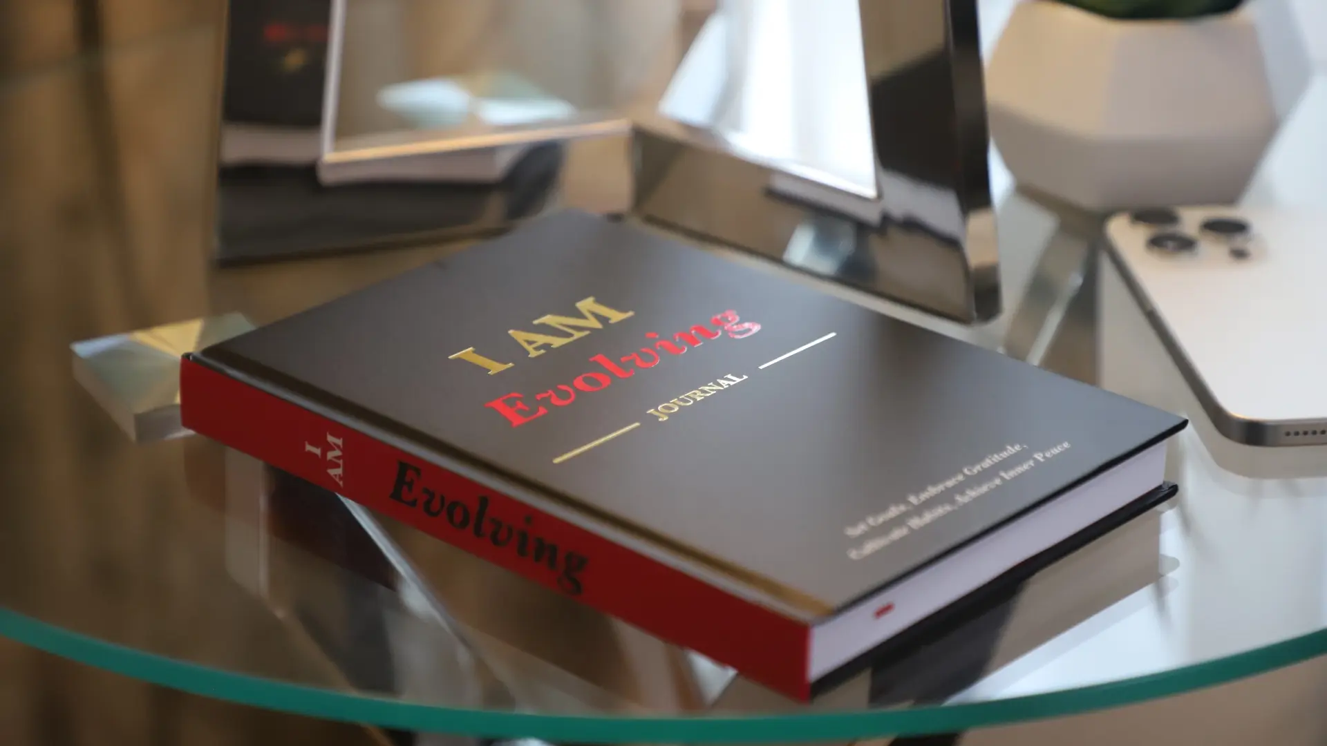 Black cover I AM Evolving Journal personal planner on a glass table – lifestyle photo