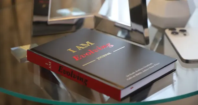 Black cover I AM Evolving Journal personal planner on a glass table – lifestyle photo