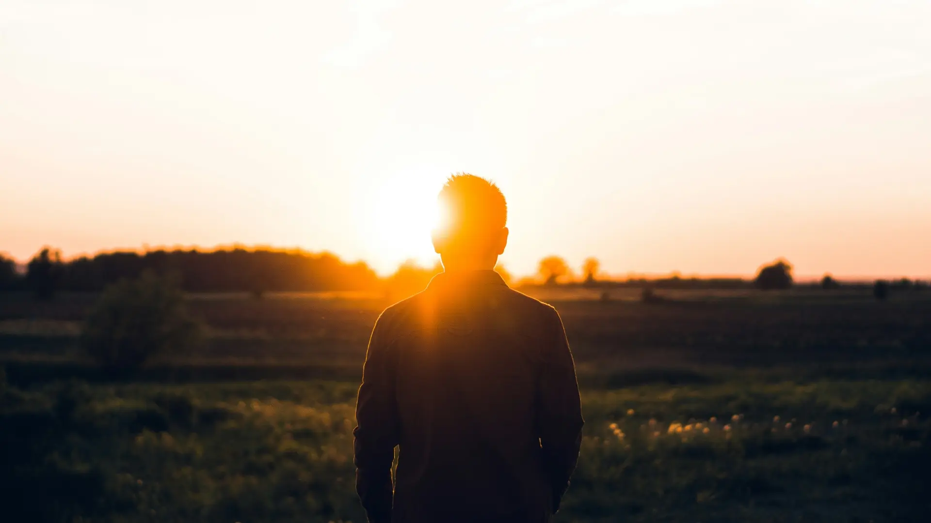 Person standing in a field at sunrise, symbolizing confidence, gratitude, and personal growth