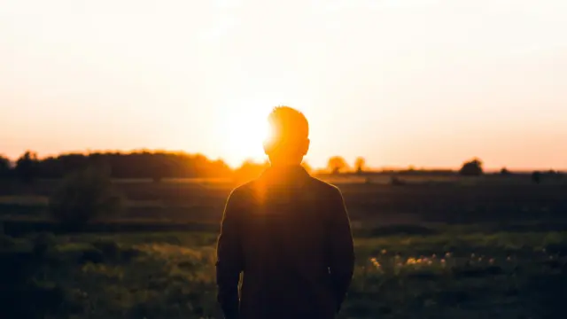 Person standing in a field at sunrise, symbolizing confidence, gratitude, and personal growth