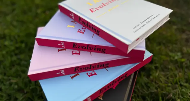 Stack of iAmEvolving Journals in different colors on the grass