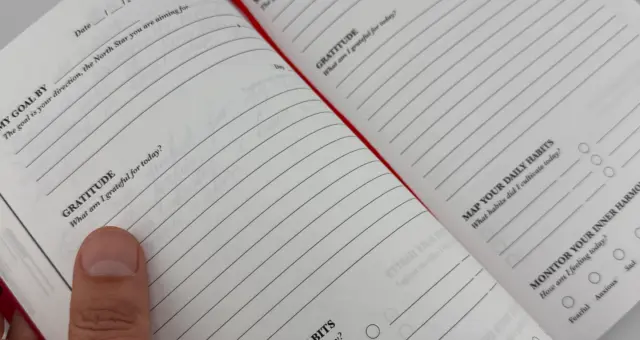 iAmEvolving Journal on a desk beside a pen and notebook, representing goal setting and planning
