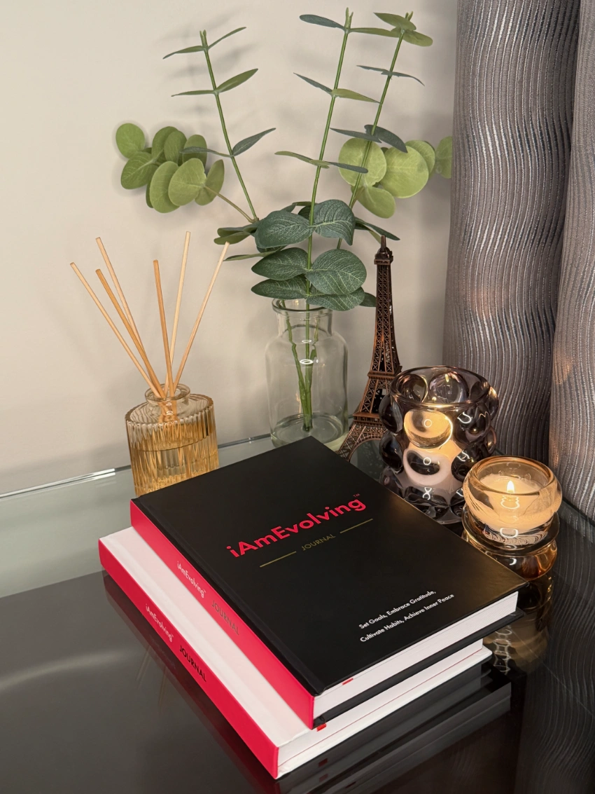 Stack of two iAmEvolving™ Black Journals displayed with candles and décor — daily journal for goals, habits, and gratitude.