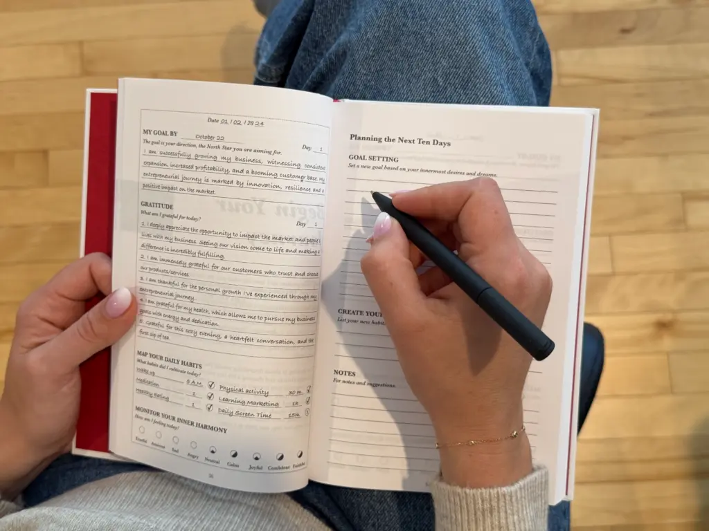 Person writing in a guided journal focusing on goals, gratitude, and habits