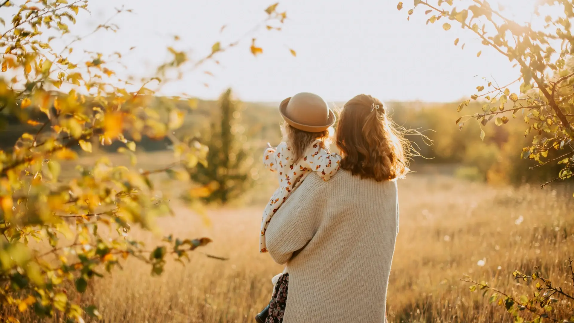 Mother holding child in a golden autumn field, symbolizing personal growth, change, and emotional connection.