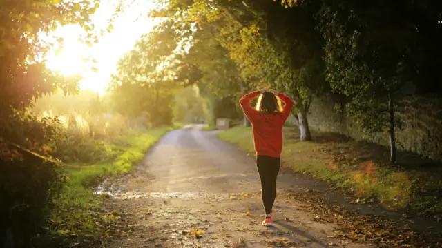 A person walking on a sunlit path in nature, symbolizing self-awareness and personal growth.