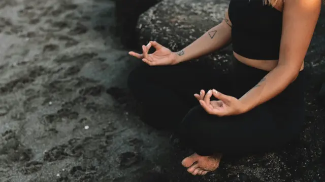 Woman meditating on the beach, reconnecting with herself through mindfulness.