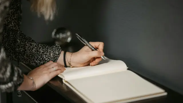 Woman starting a gratitude journaling practice by writing in a blank notebook.