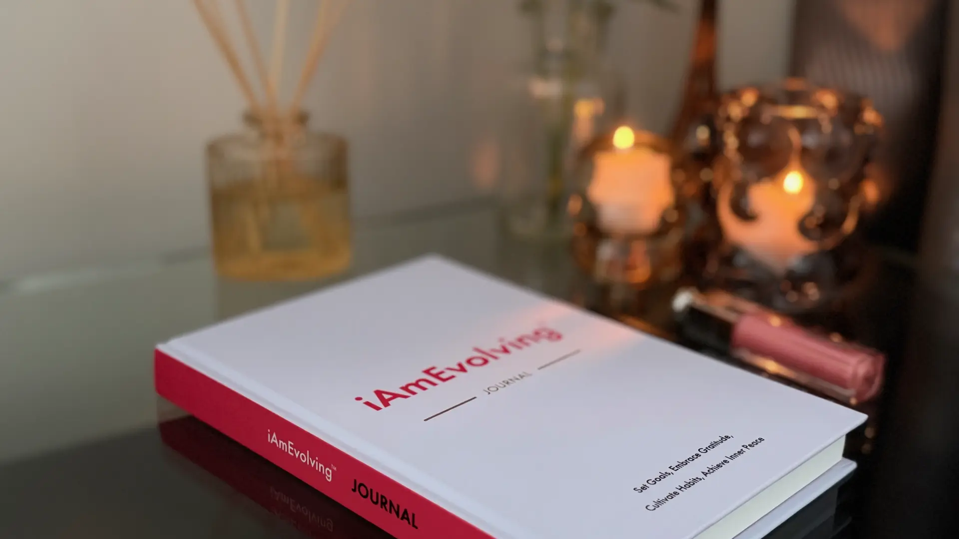 iAmEvolving Journal on a reflective table beside candles and diffuser, creating a calm winter atmosphere for mindful year-end reflection