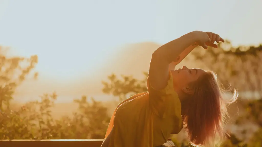 Woman stretching in morning sunlight, representing the Affirmations Guide practice of mindful self-talk and emotional renewal