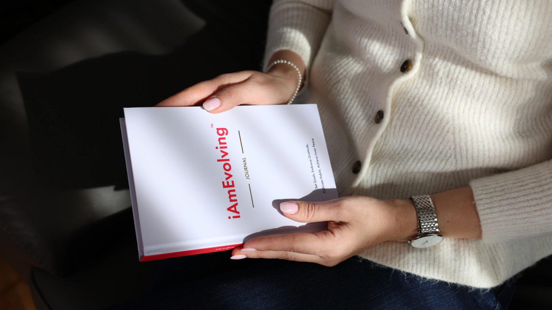 Close-up of hands holding the iAmEvolving Journal, symbolizing mindful daily routines and personal growth practices.