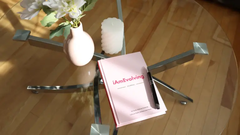 iAmEvolving Journal on a glass table with morning light — symbolizing emotional alignment and mindful goal setting.