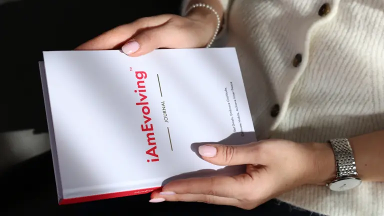 “Person holding the iAmEvolving Journal in soft light — a moment of reflection before writing gratitude prompts
