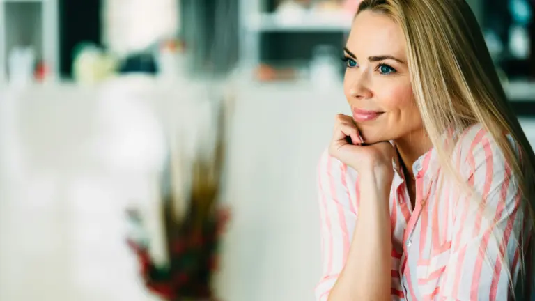Woman smiling thoughtfully in natural light, symbolizing clarity, self-alignment, and living with purpose.
