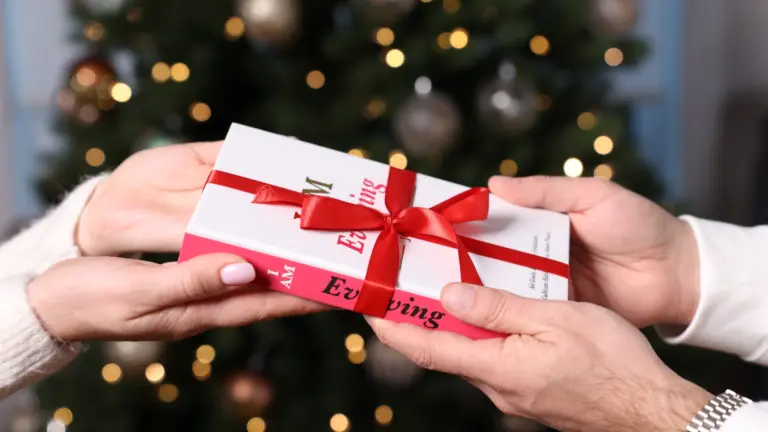 Hands exchanging a beautifully wrapped iAmEvolving journal as a mindful holiday gift.