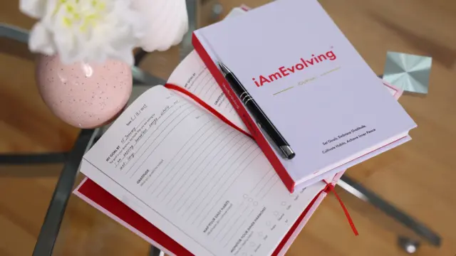 iAmEvolving Journal open on a table with a pen, symbolizing reflection, clarity, and personal growth.