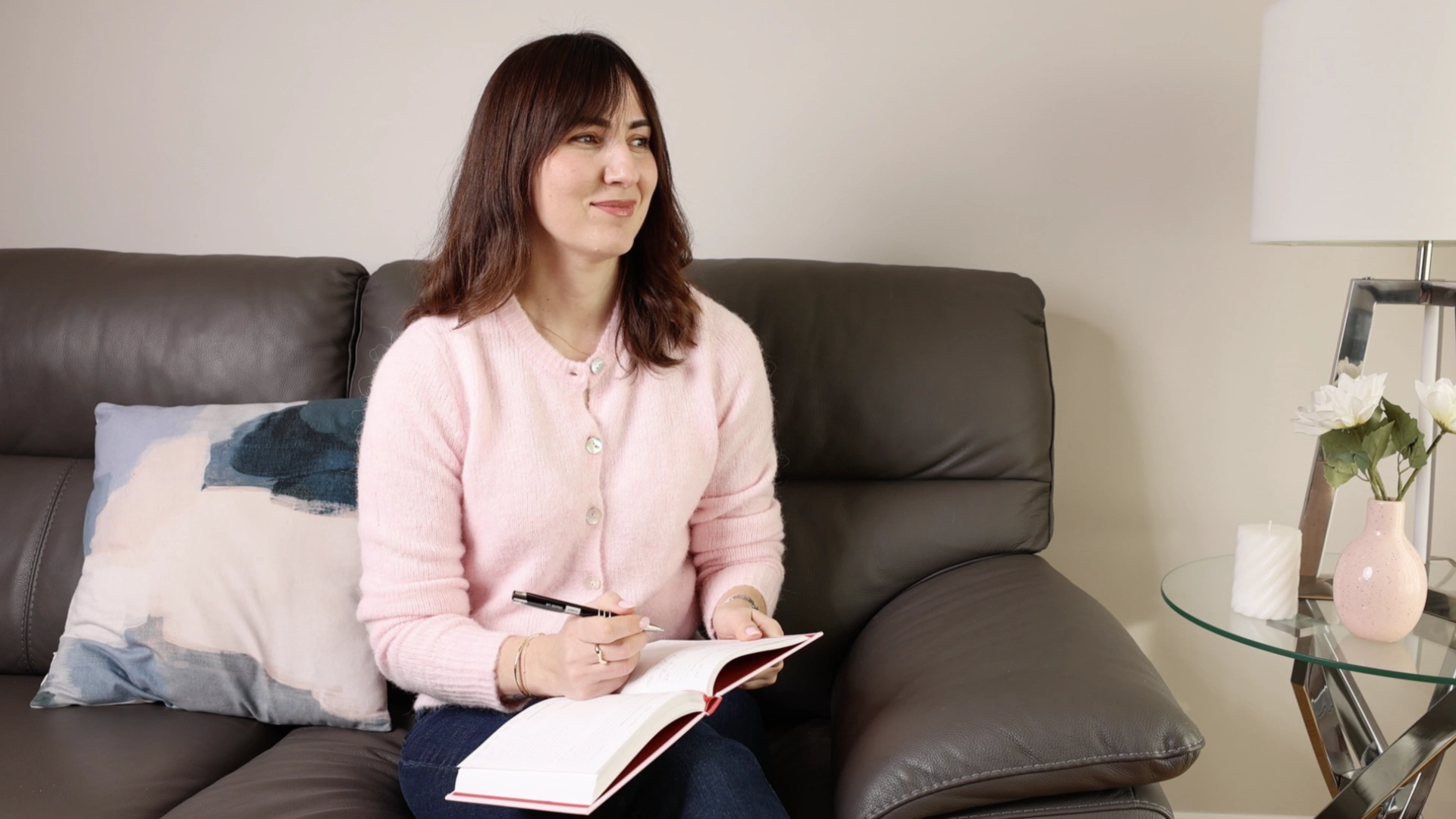 Woman journaling on a couch, reflecting on personal growth and self-awareness.