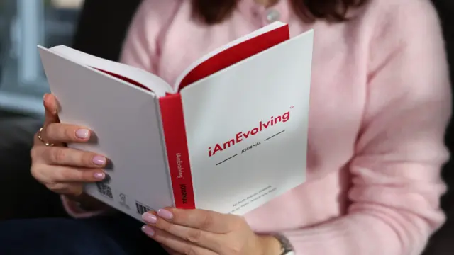 Person reading the iAmEvolving Journal, reflecting on personal goals and mindful growth