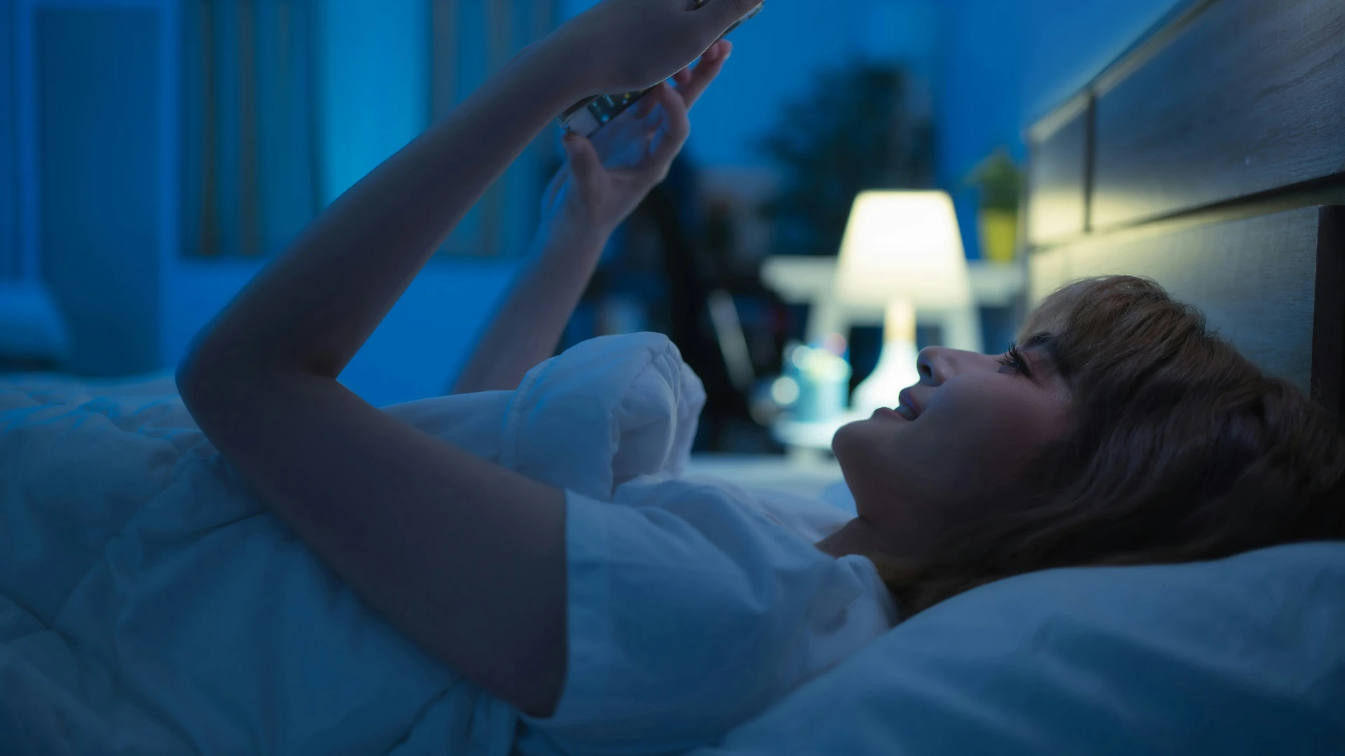 Woman winding down in bed at night, creating a peaceful evening routine before sleep