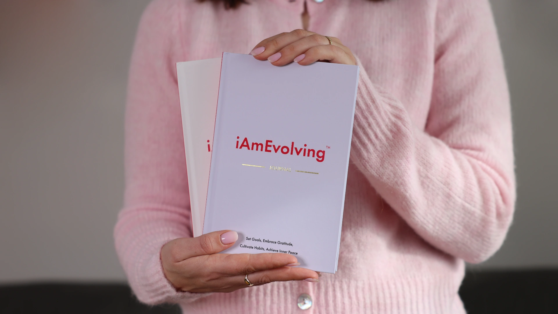 Person holding two iAmEvolving Journals, representing a grateful journal practice for mindful gratitude and daily reflection.