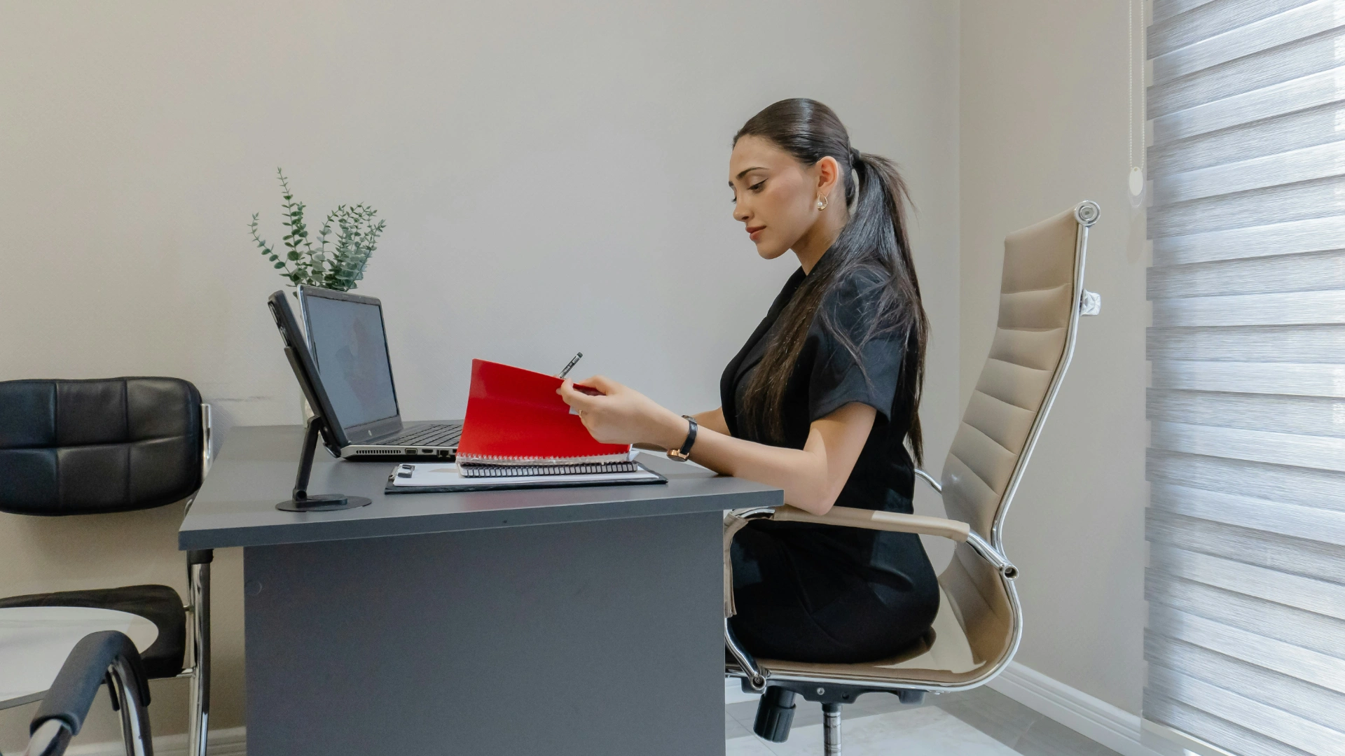 Professional woman reflecting at desk with journal and laptop – managing mental load at work.