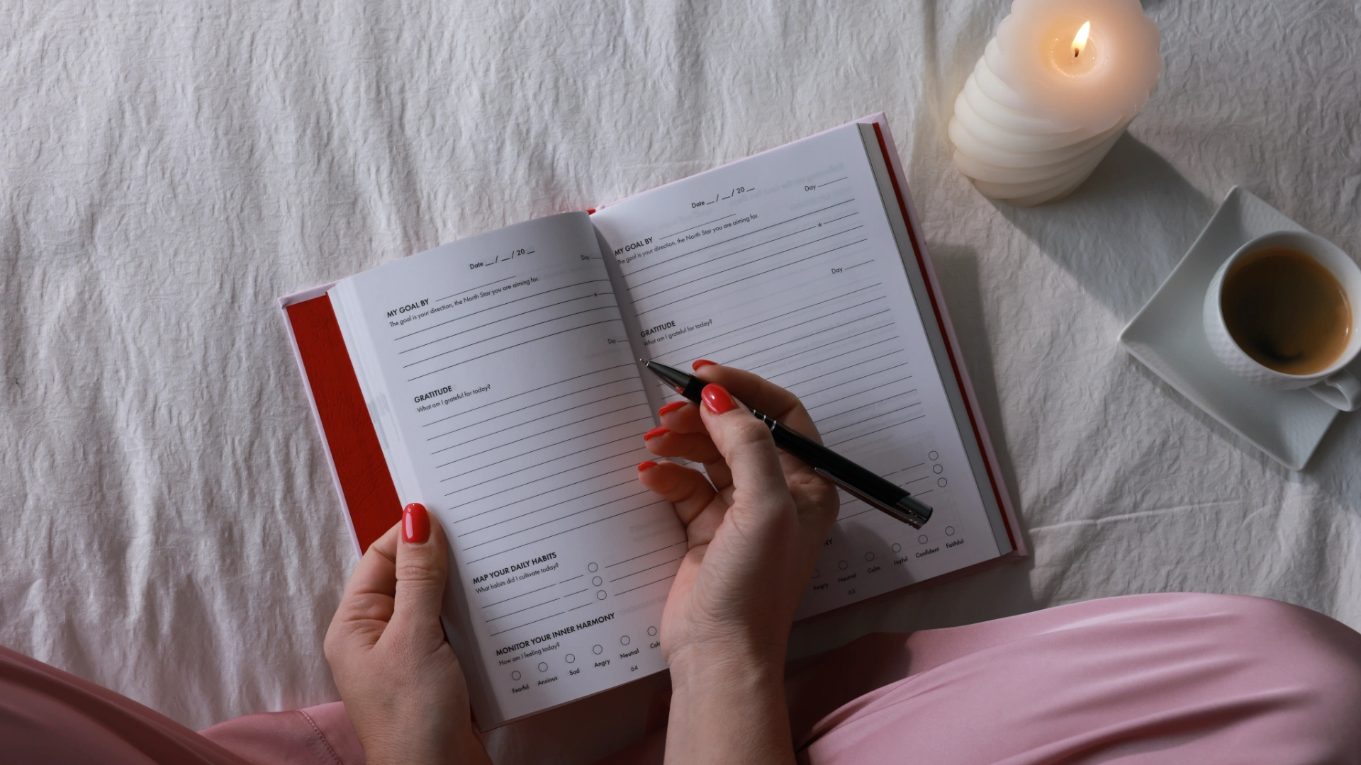 Woman writing in iAmEvolving Journal as part of daily affirmation rituals with candle and coffee