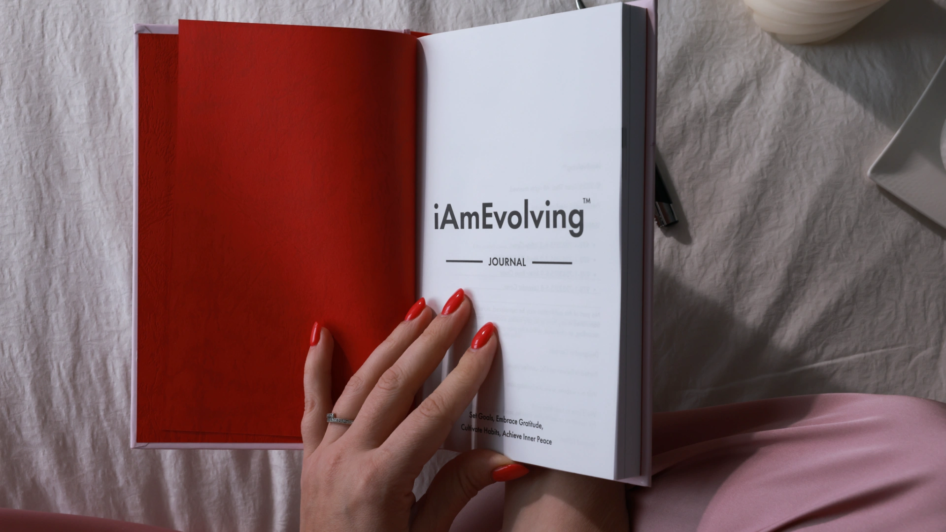 Woman holding open iAmEvolving Journal for evening affirmations and reflection before bed