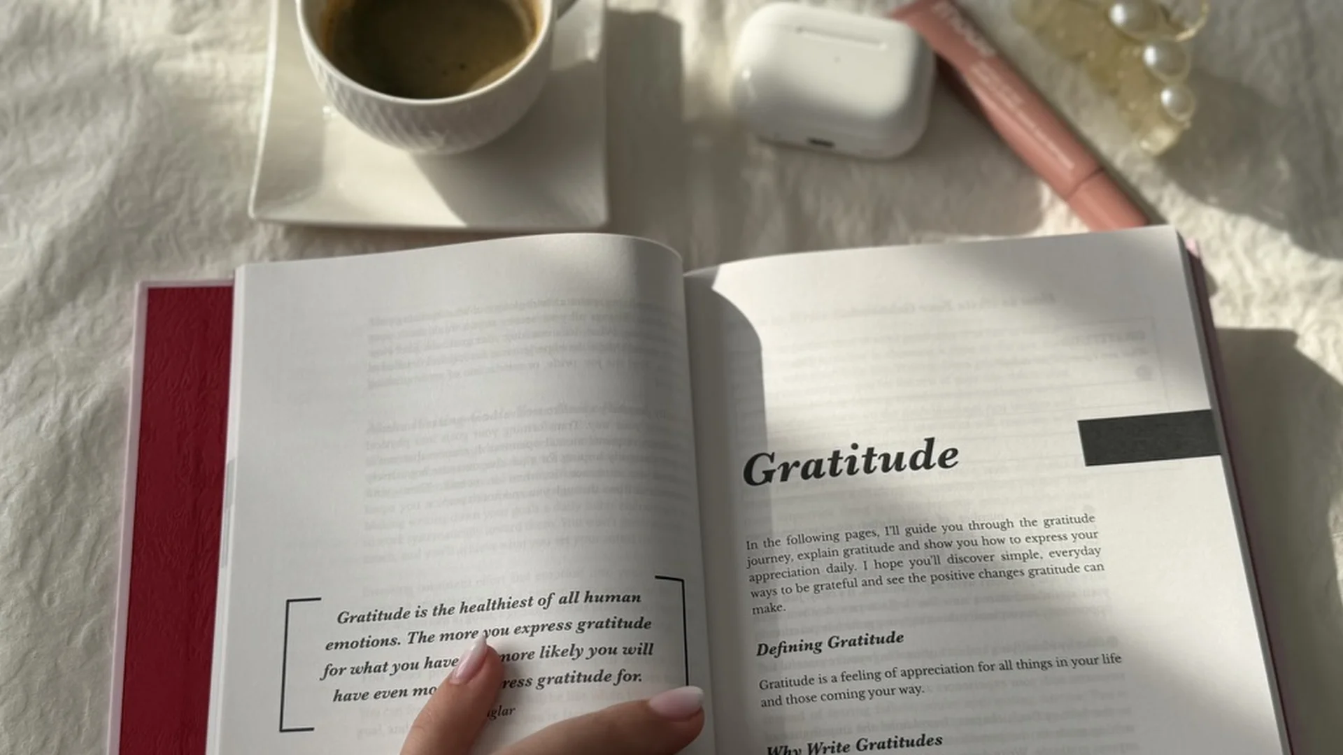 Open gratitude journal with coffee and AirPods on a white bed — 30-day gratitude challenge