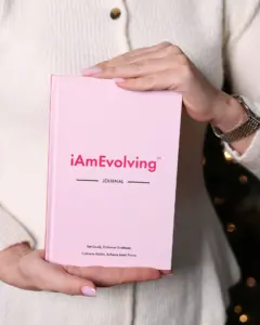 Woman holding iAmEvolving Journal rose edition in cozy setting