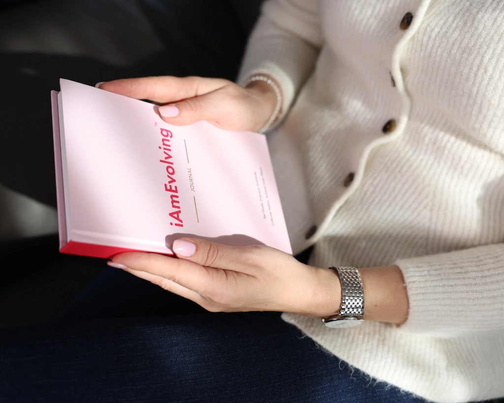 Woman holding the iAmEvolving Journal open to the title page, cozy cream sweater and silver watch