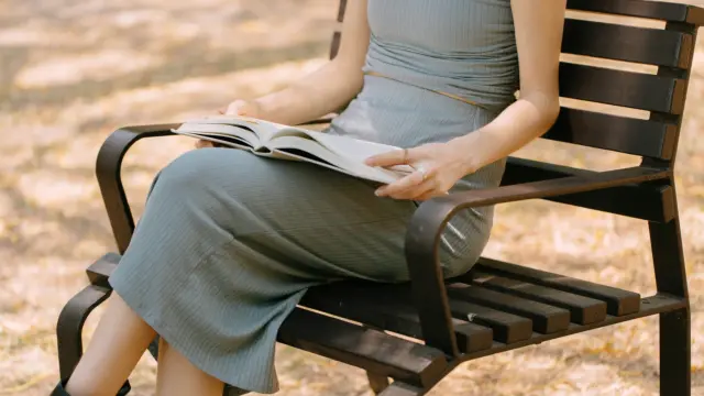 Woman sitting on a park bench with an open journal in warm golden light