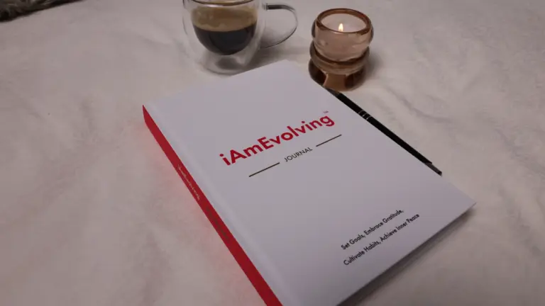 iAmEvolving Journal on a white surface with espresso and a candle, representing a journaling practice for men