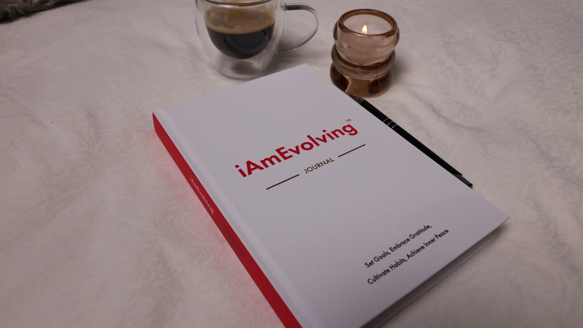 iAmEvolving Journal on a white surface with espresso and a candle, representing a journaling practice for men