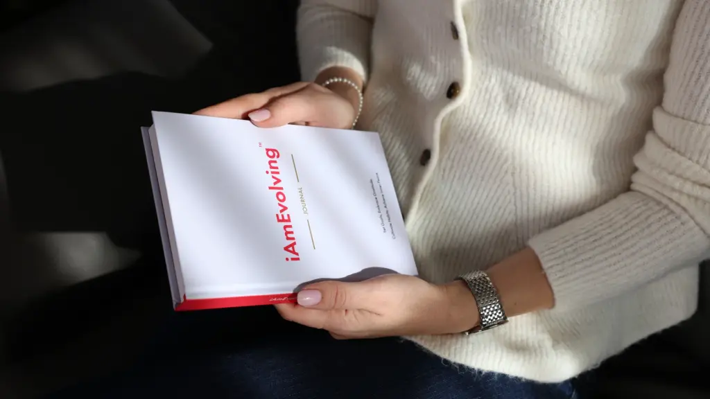 Woman holding the iAmEvolving Journal, using it as a manifestation journal to write down goals and intentions